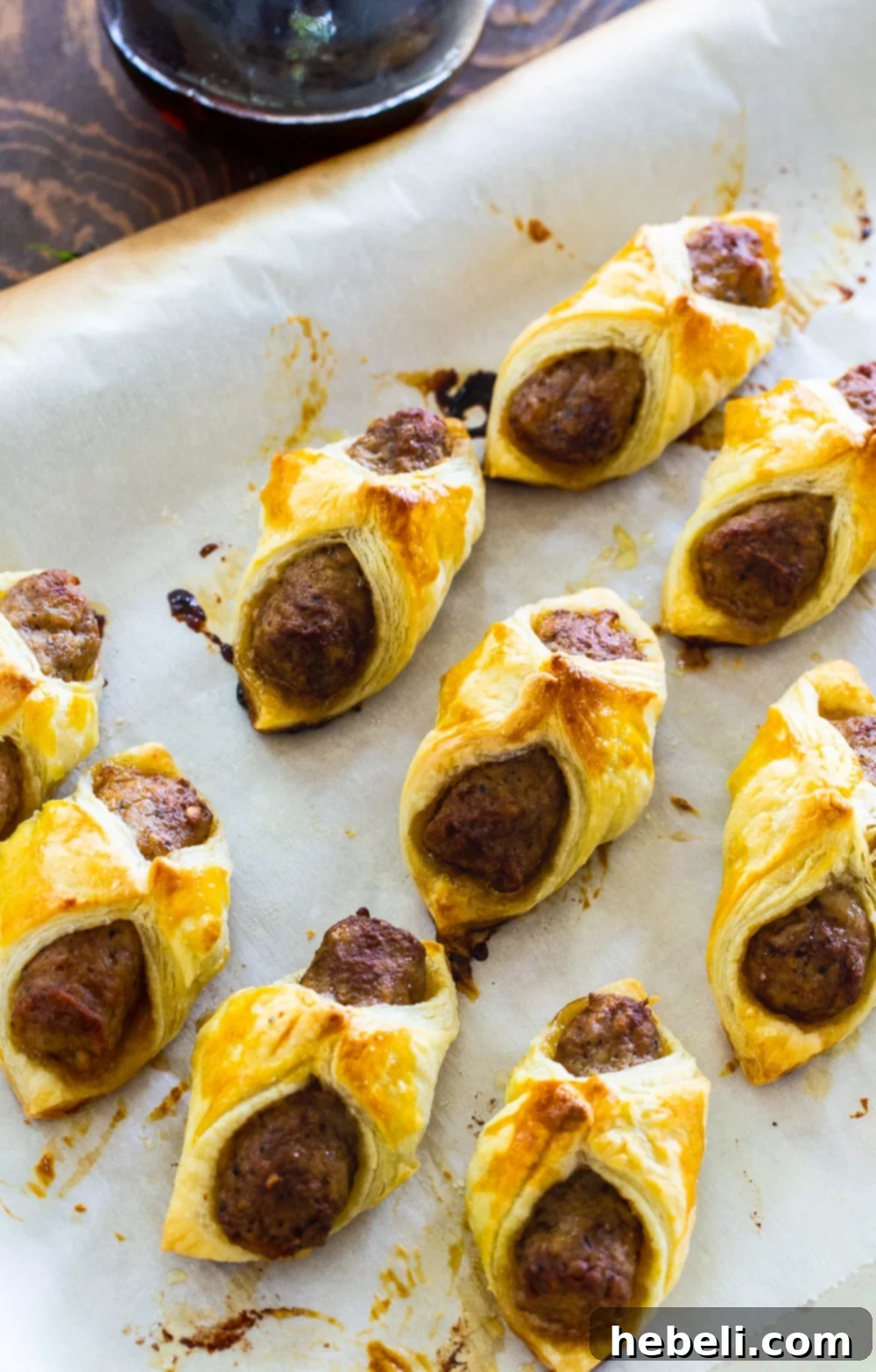Sausages wrapped in puff pastry on a baking sheet, ready for the oven.
