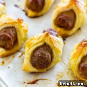 Breakfast Pigs in a Blanket, perfectly golden brown on parchment paper.