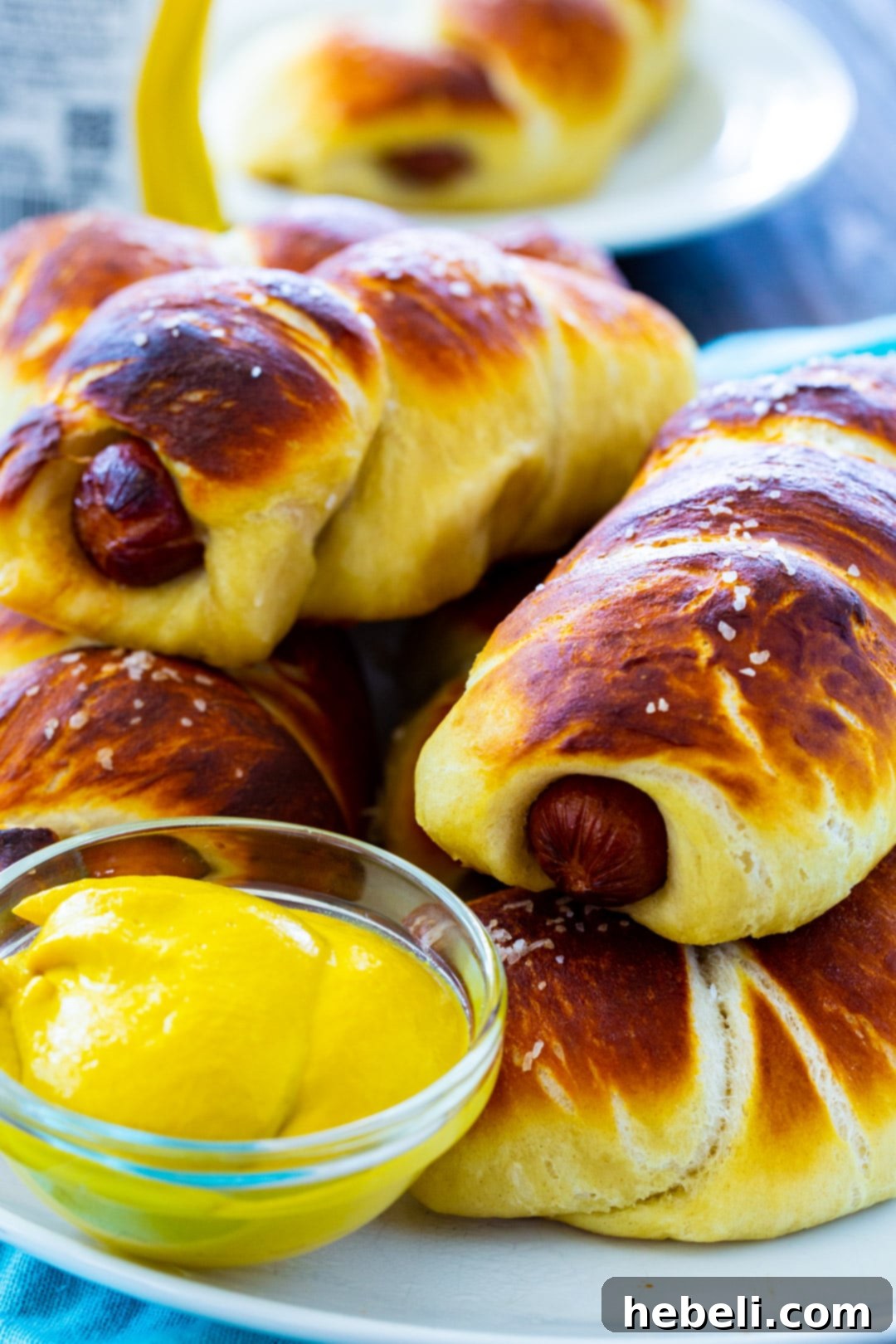 Two golden brown homemade Pretzel Dogs, lightly salted, resting on a white plate, showcasing their perfect bake.