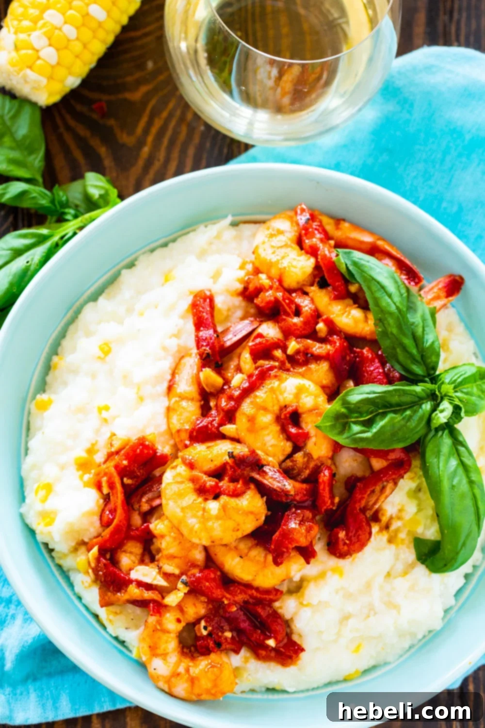 Closeup of creamy Shrimp and Grits in a light blue bowl, garnished with herbs.