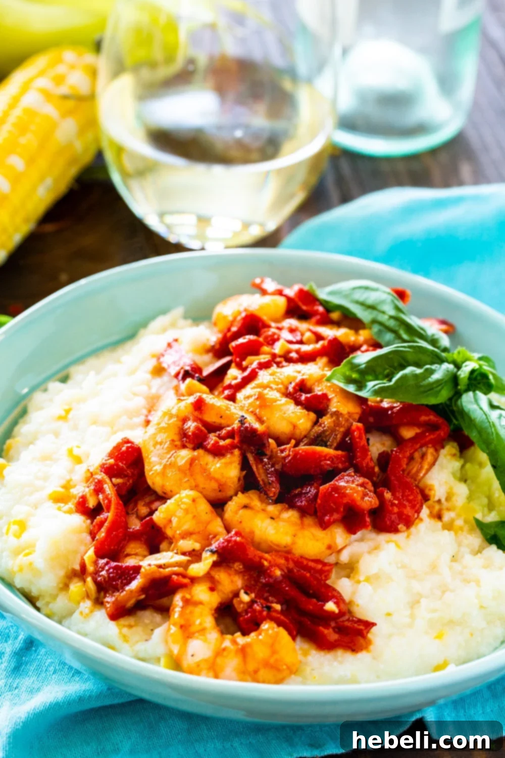Shrimp and Goat Cheese Grits with Roasted Red Pepper Sauce served in a bowl with a glass of white wine.