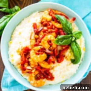 Shrimp and Goat Cheese Grits with Roasted Red Pepper Sauce in a blue bowl with basil.