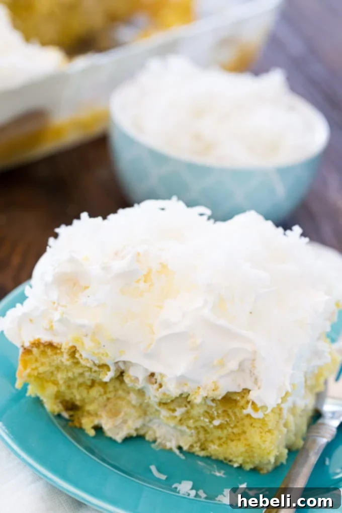 Close-up of a beautifully decorated Coconut Cream Poke Cake, garnished with ample shredded coconut on a white whipped topping.