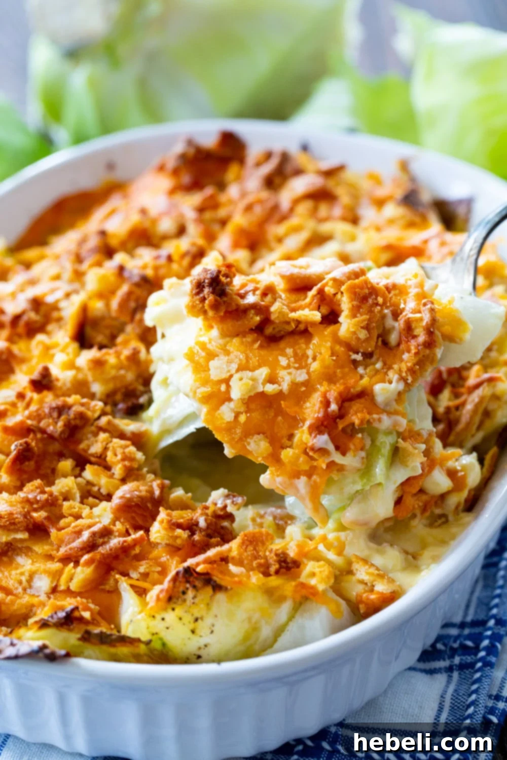 A serving spoon lifting a generous portion of creamy Old-Fashioned Cabbage Casserole.