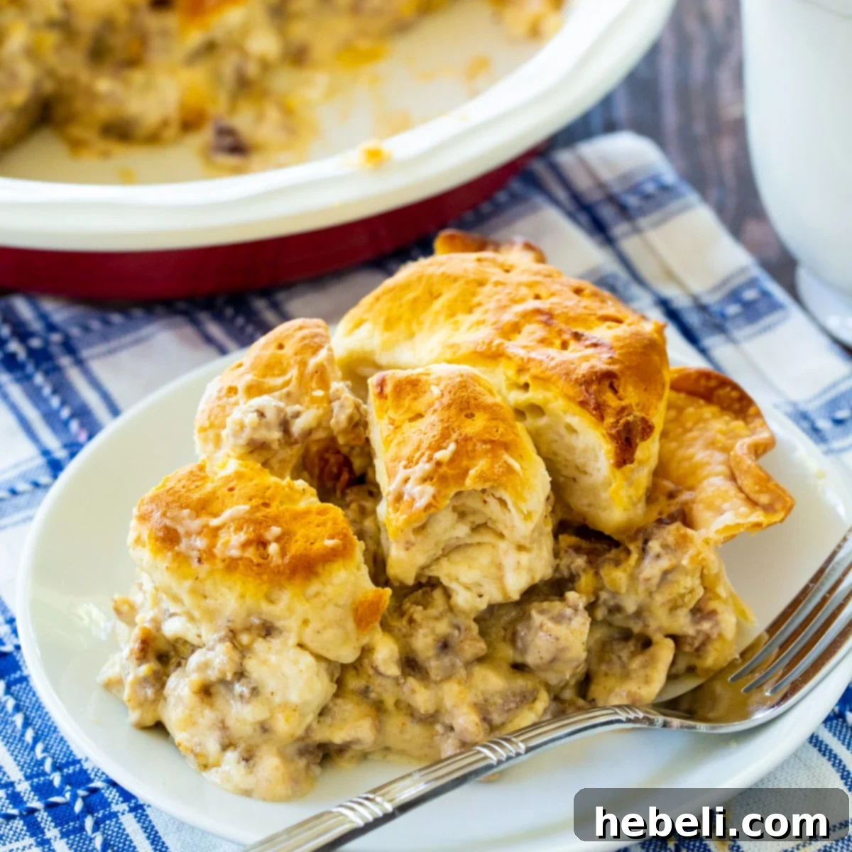 Homestyle Gravy & Biscuit Pie 2 A delectable slice of Biscuits and Gravy Pie, showcasing the creamy sausage gravy, golden crust, and fluffy biscuit topping, served on a white plate ready to be enjoyed.