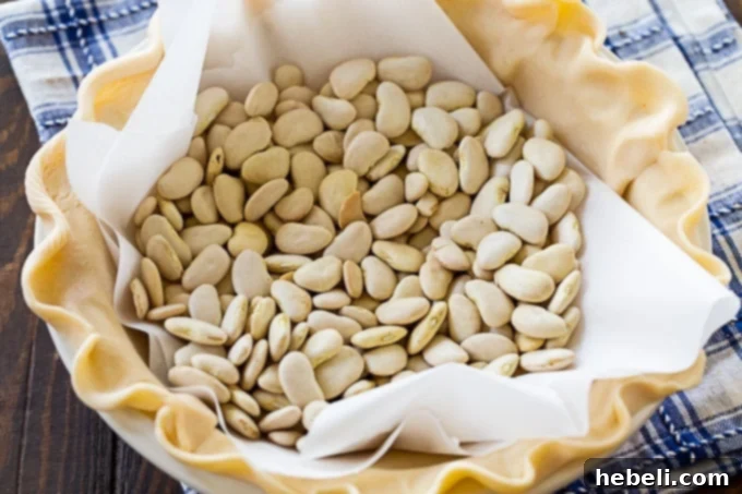 Homestyle Gravy & Biscuit Pie 4 Raw pie crust lined with parchment paper and pie weights, ready for pre-baking.