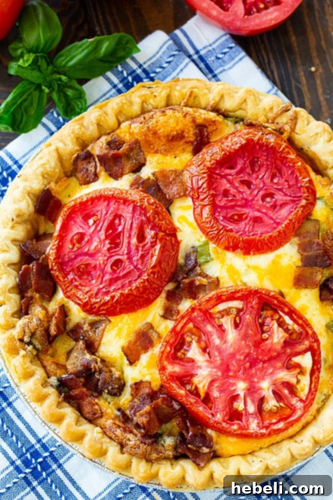 A slice of Tomato Pie with Bacon, revealing layers of ripe tomatoes, crispy bacon, and melted cheese, ready to be enjoyed.