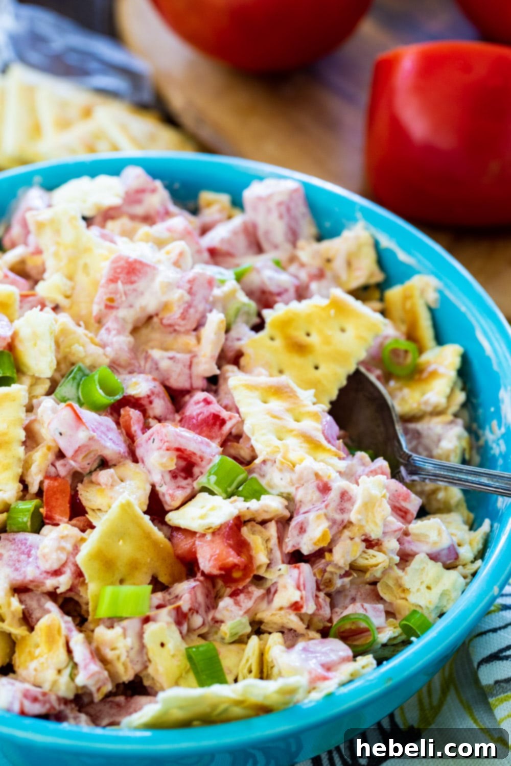Tomato Cracker Salad in a blue bowl with a serving spoon.