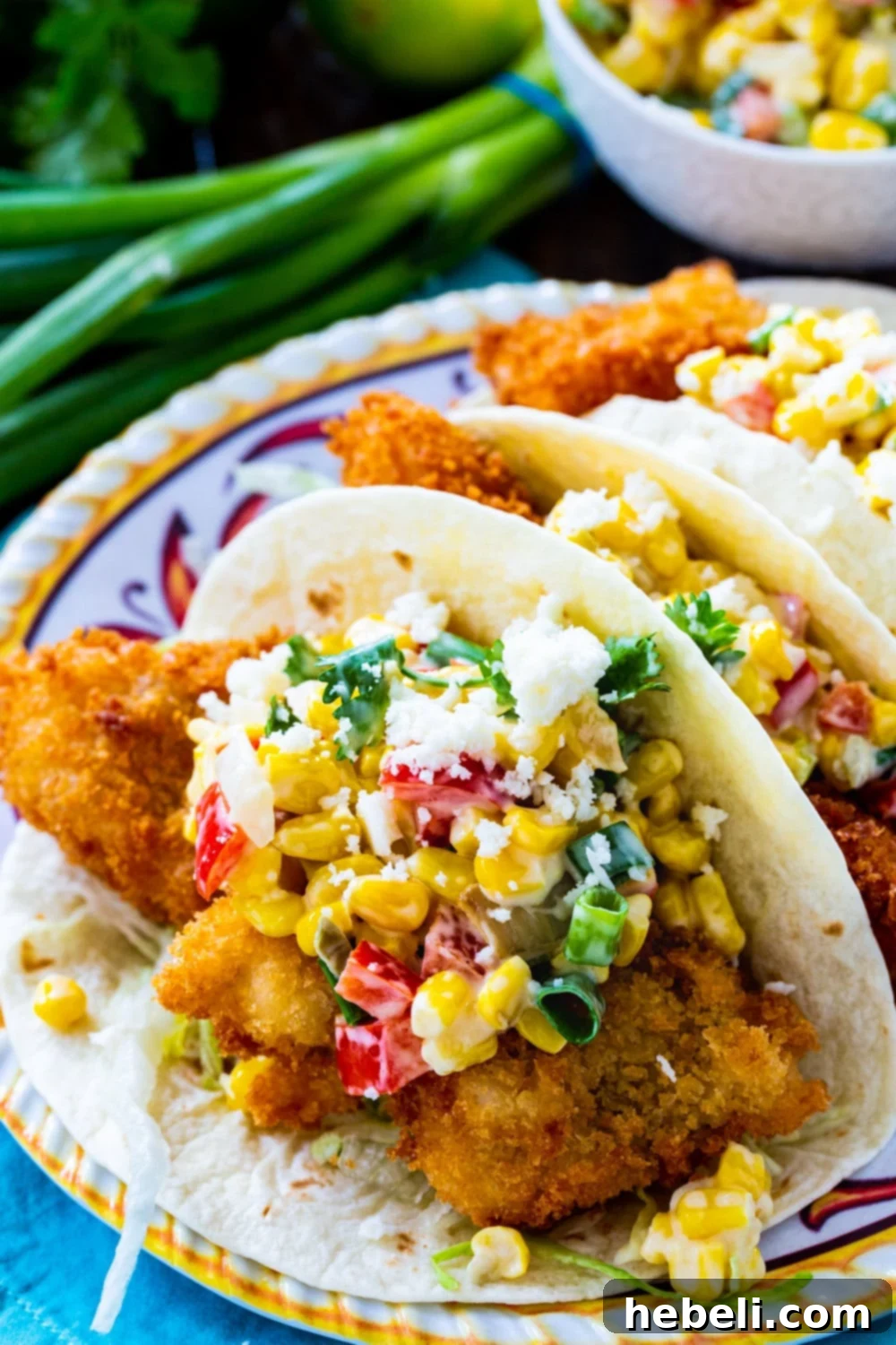 Crispy Catfish Tacos with Tequila Spiked Creamed Corn 3 Tacos topped with Tequila Creamed Corn on a plate, ready to be served.