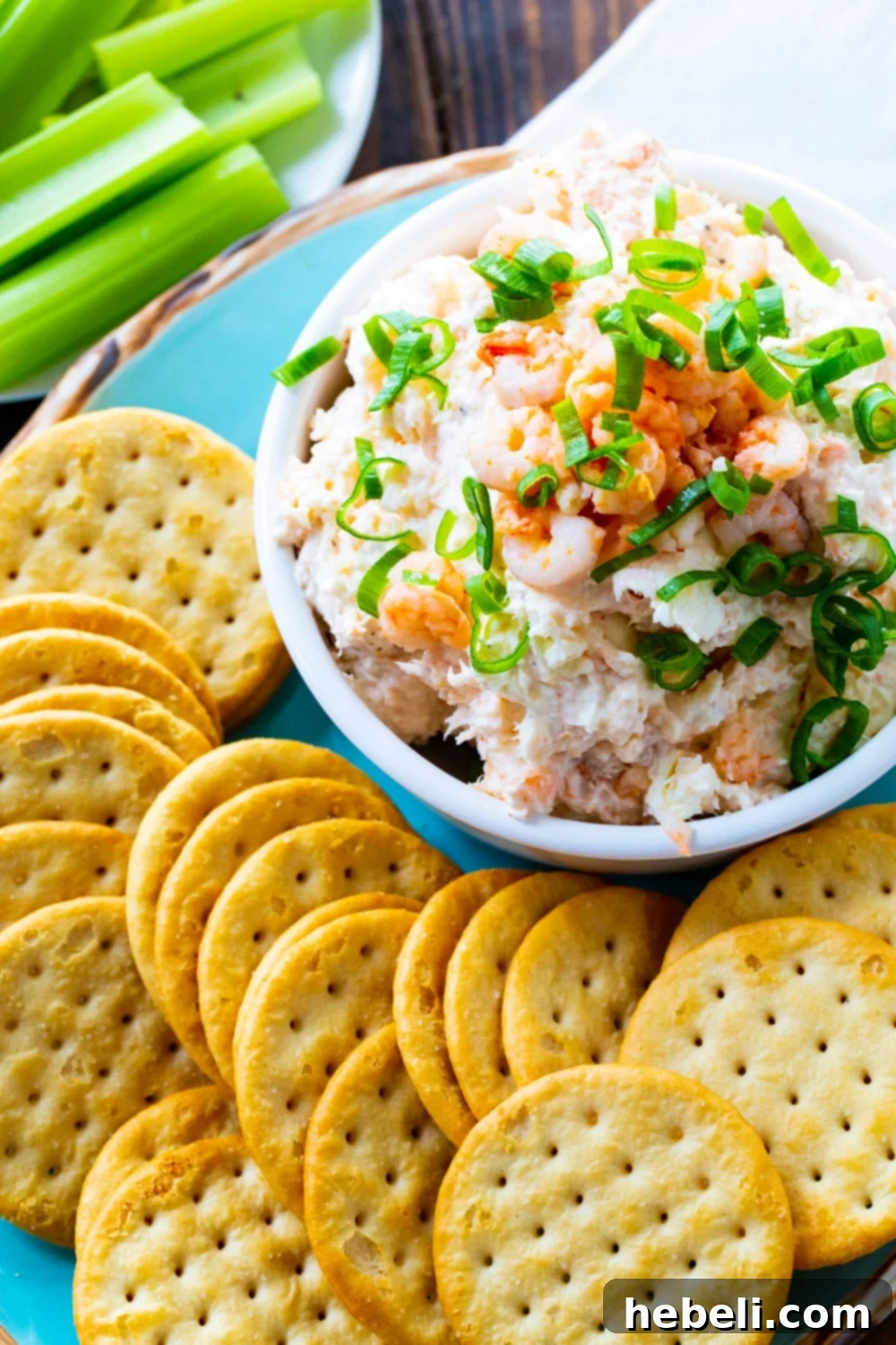 Close-up of creamy Shrimp Spread in a serving bowl with fresh green onions and crackers.