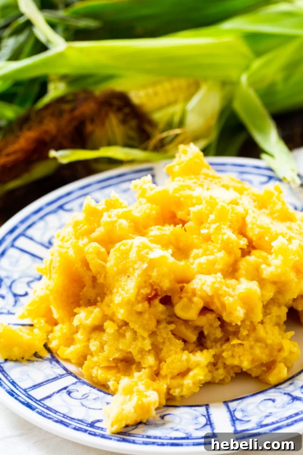 A delicious serving of golden-brown Crock Pot Corn Casserole presented on a pristine white plate, garnished with a sprinkle of fresh green herbs.