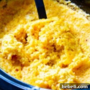 Close-up of a serving spoon scooping a portion of golden, creamy Crock Pot Corn Casserole, indicating its readiness.