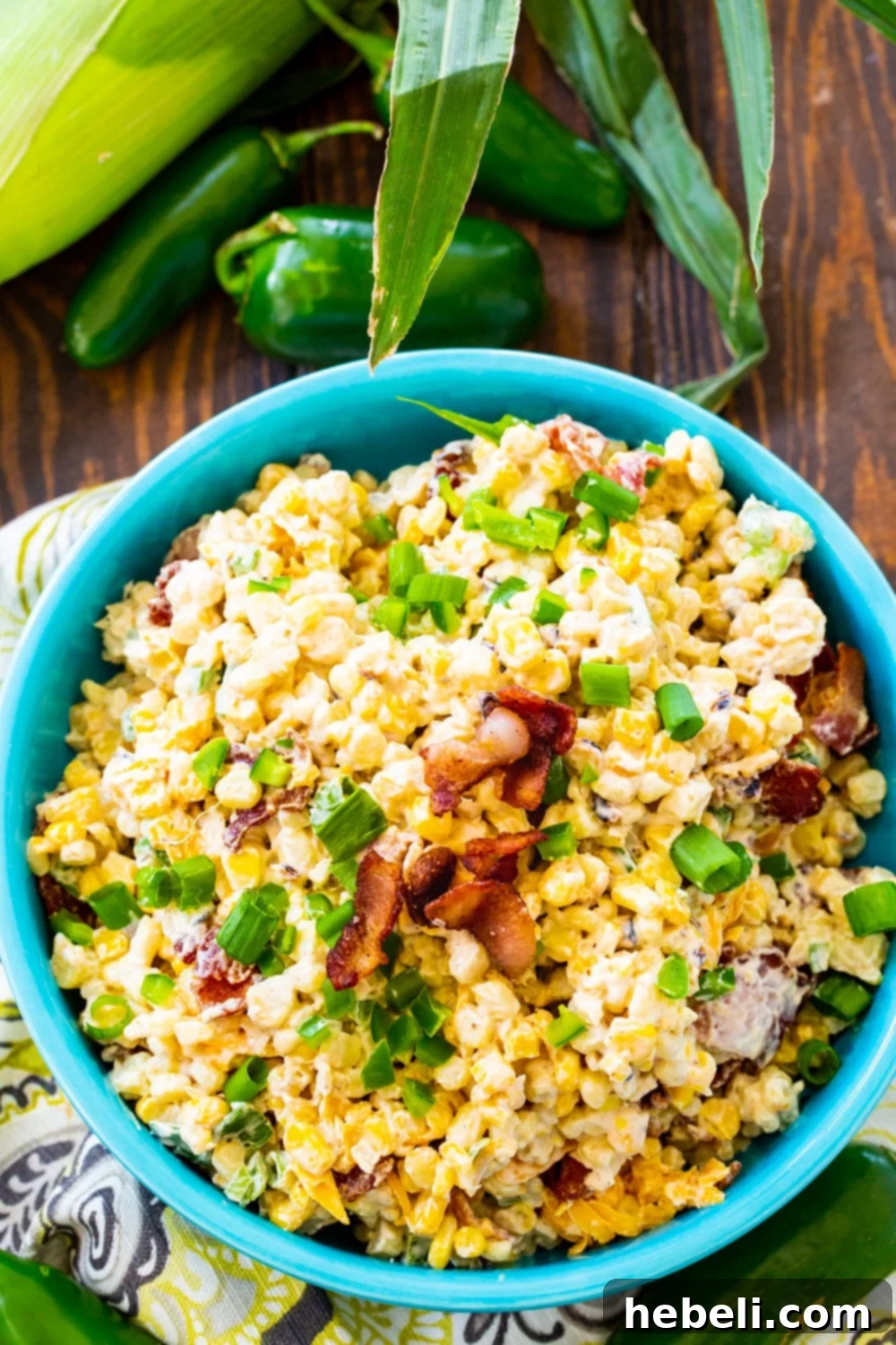 Corn Salad in a blue bowl with ears of corn next to it.