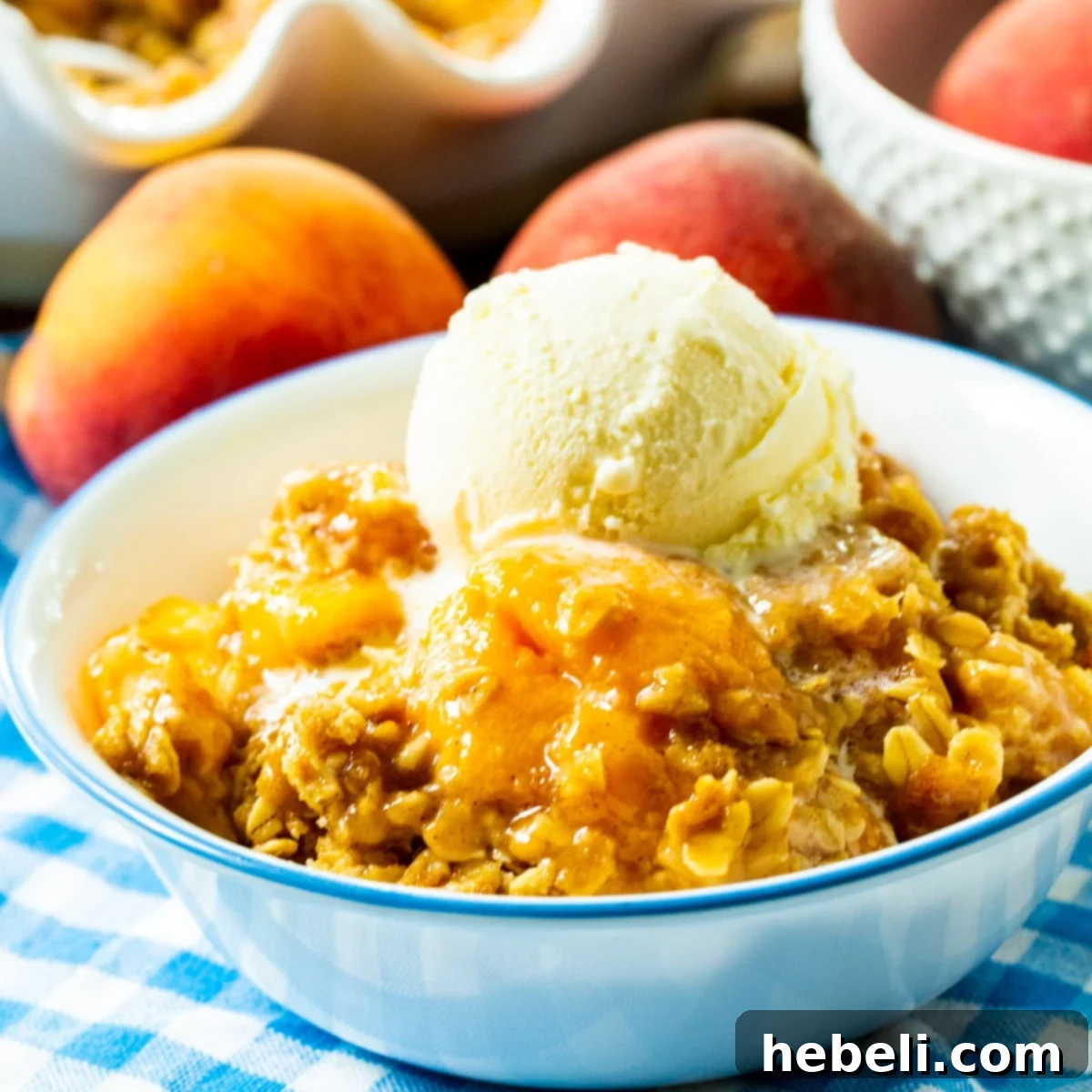 Warm Spiced Peach Bake 2 Peach Crisp topped with ice cream in a bowl.
