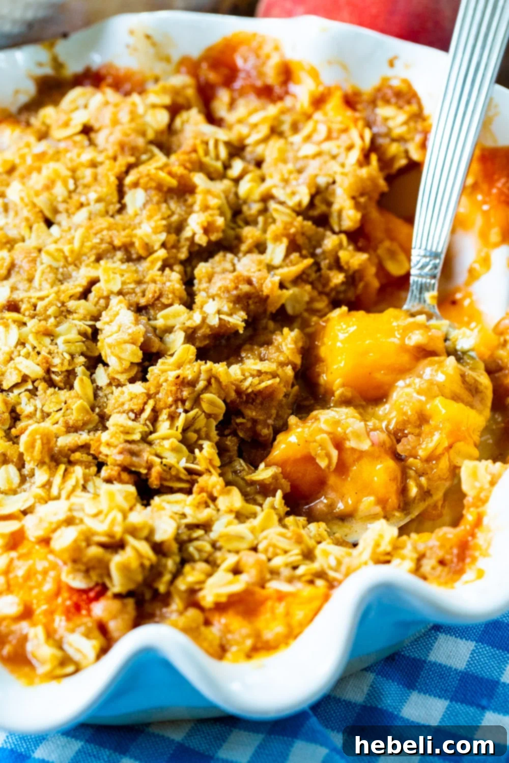Warm Spiced Peach Bake 4 Spoon scooping Peach Crisp out of pie pan.