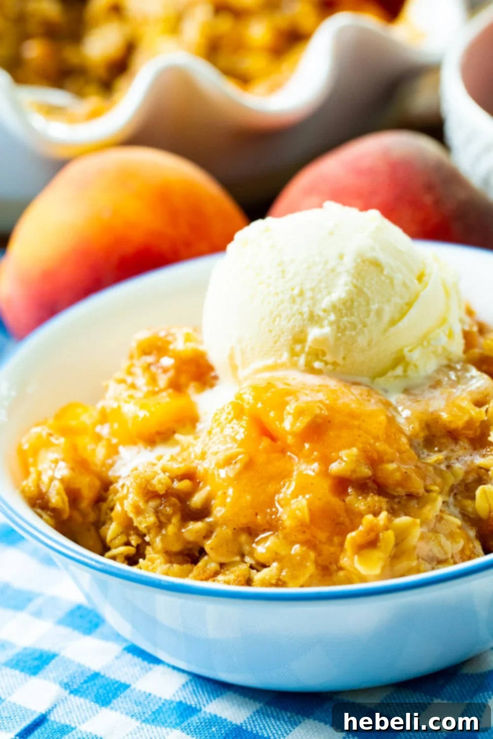 Warm Spiced Peach Bake 6 Peach Crisp topped with ice cream in a bowl.