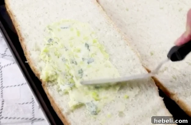 Spreading the rich butter and pepperoncini mixture onto a halved loaf of Italian bread.