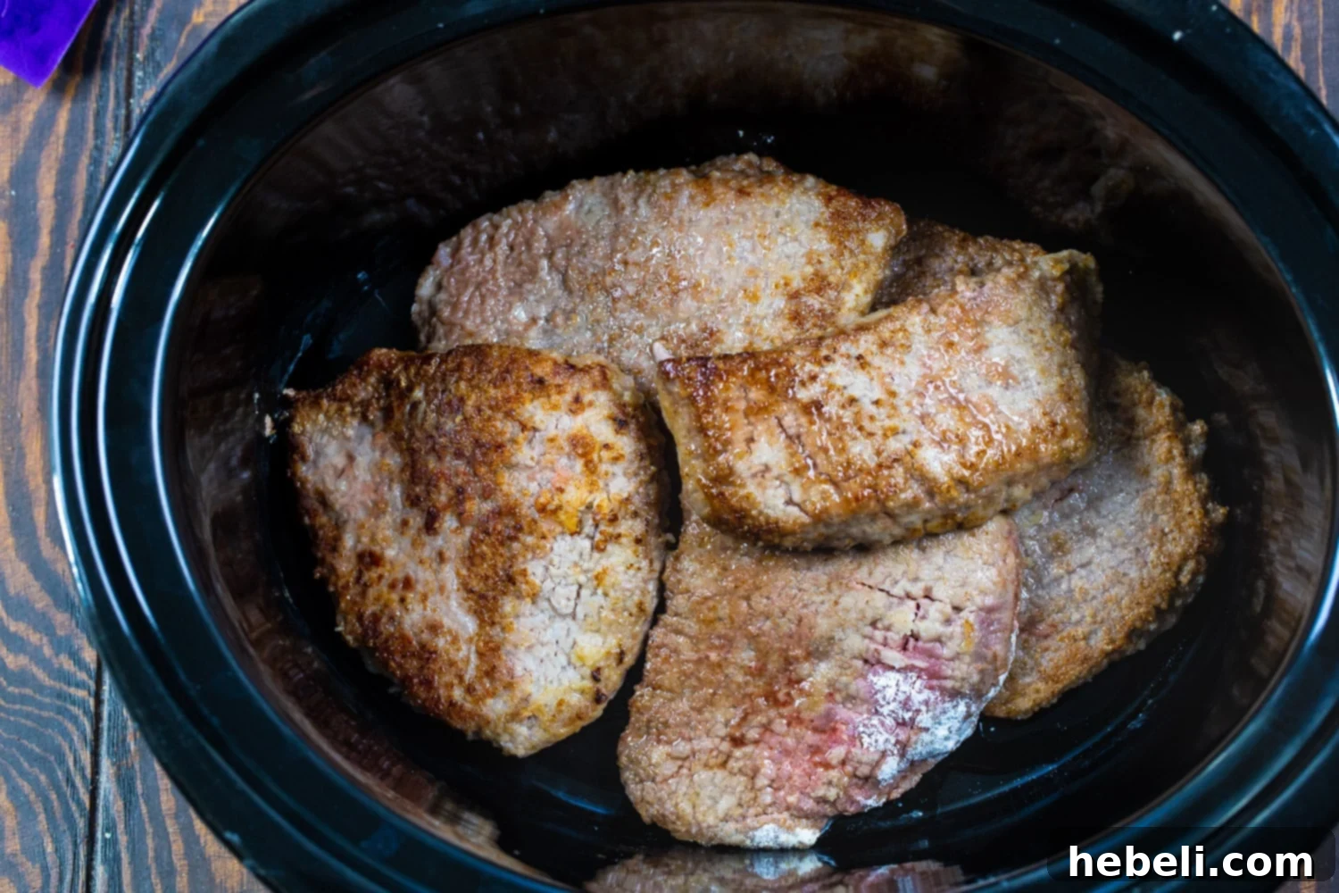Browned pieces of cubed steak in slow cooker