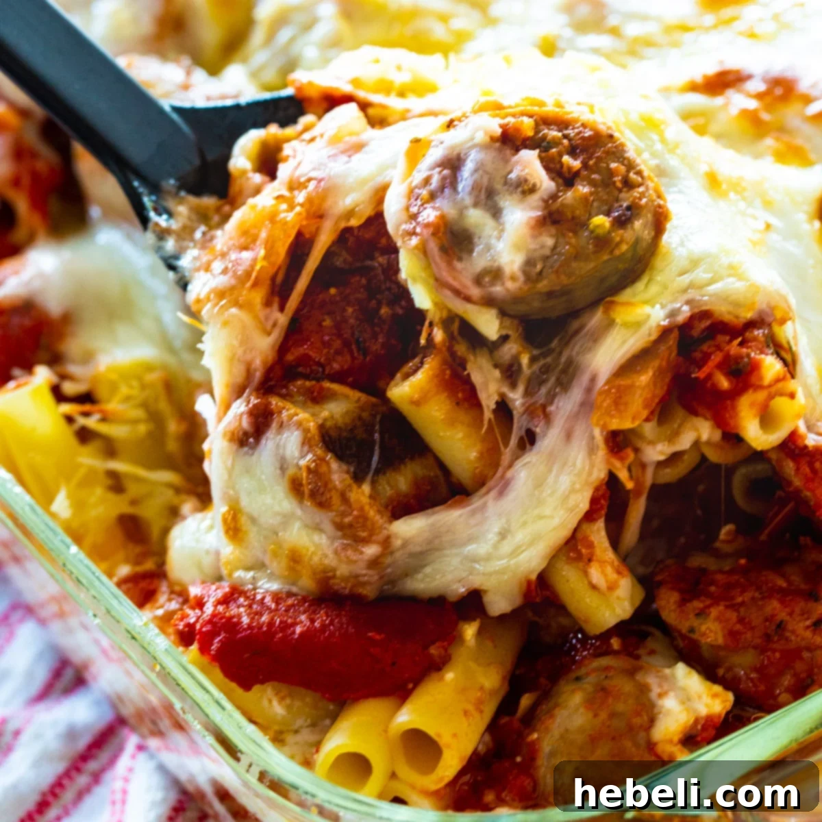 Baked Ziti with Italian Sausage getting scooped out of baking dish.