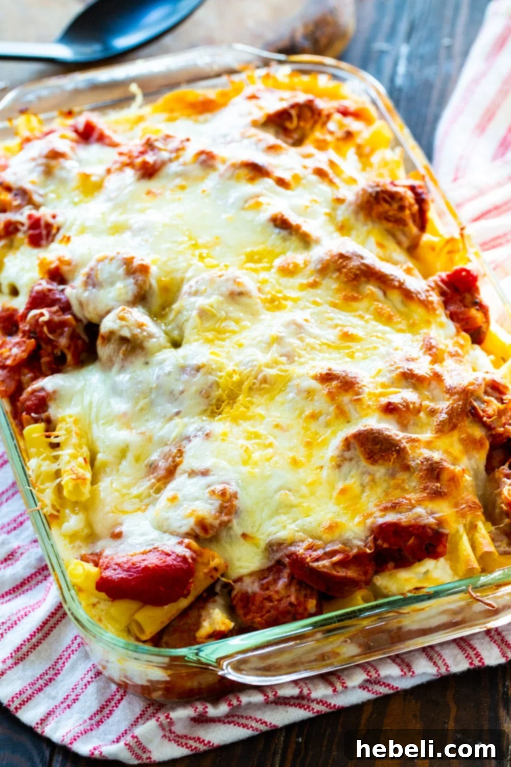 Baked ziti covered with melted cheese in baking dish.