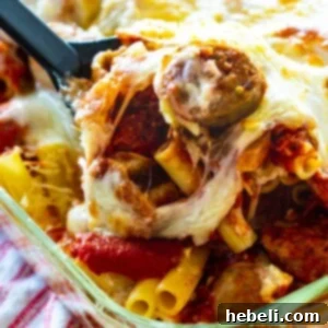 Baked Ziti with Italian Sausage getting scooped out of baking dish.