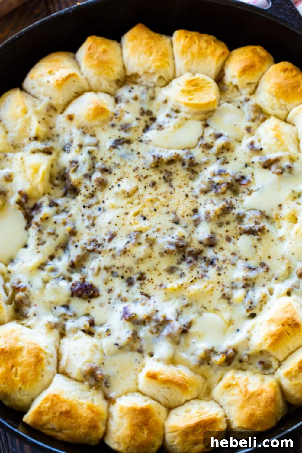 Biscuits and Gravy Ring in a cast iron pan, ready to be served, showcasing golden biscuits and creamy sausage gravy.