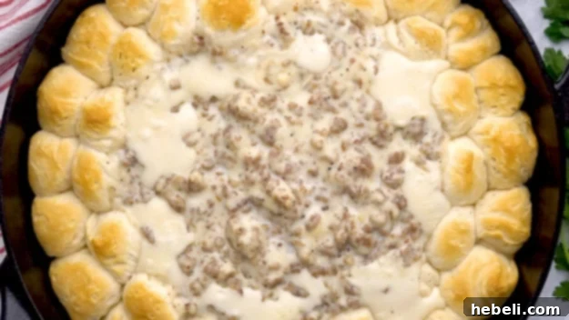 The fully baked Biscuit and Gravy Ring, golden brown and bubbling, in a cast iron skillet.