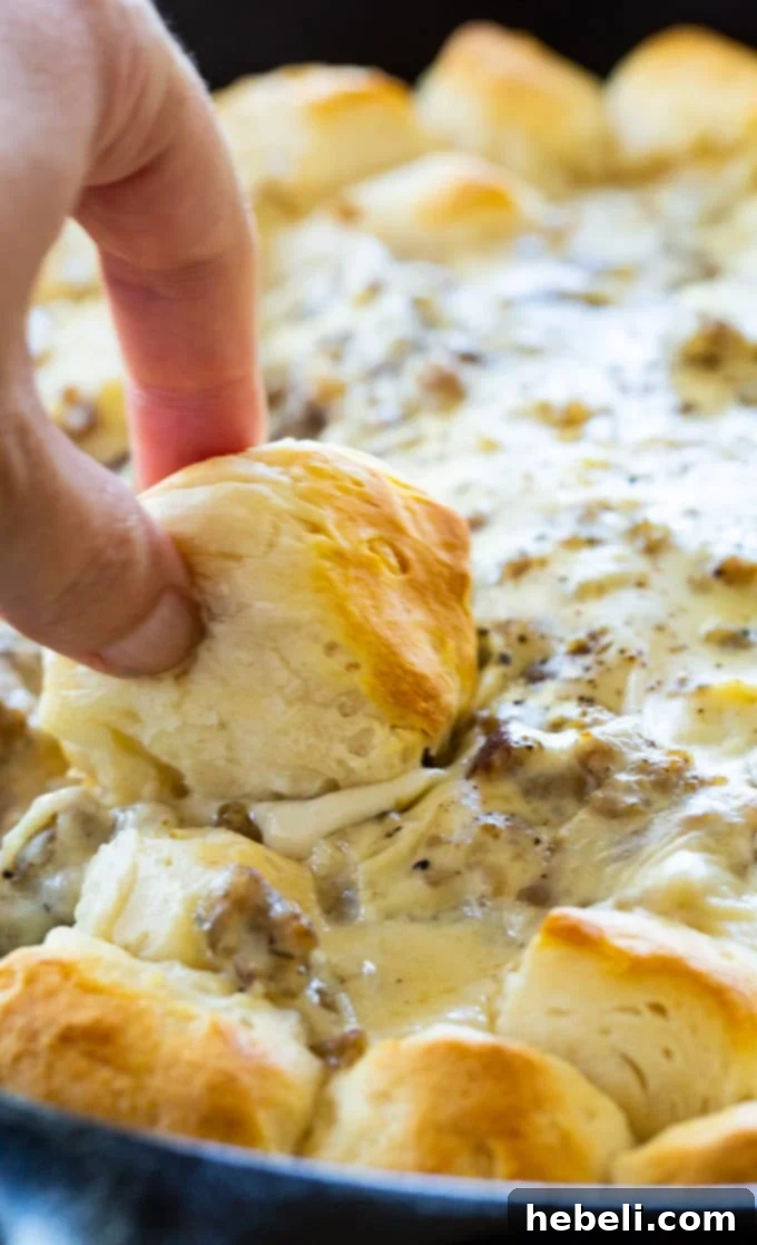 Close-up of the baked Biscuit and Gravy Ring in a cast iron skillet, showing the fluffy biscuits and rich gravy.