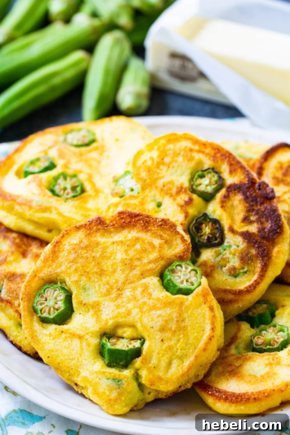 Crispy Okra Hoecakes 4 A close-up shot of several Okra Hoecakes on a plate, garnished with a pat of melting butter, ready to be enjoyed.
