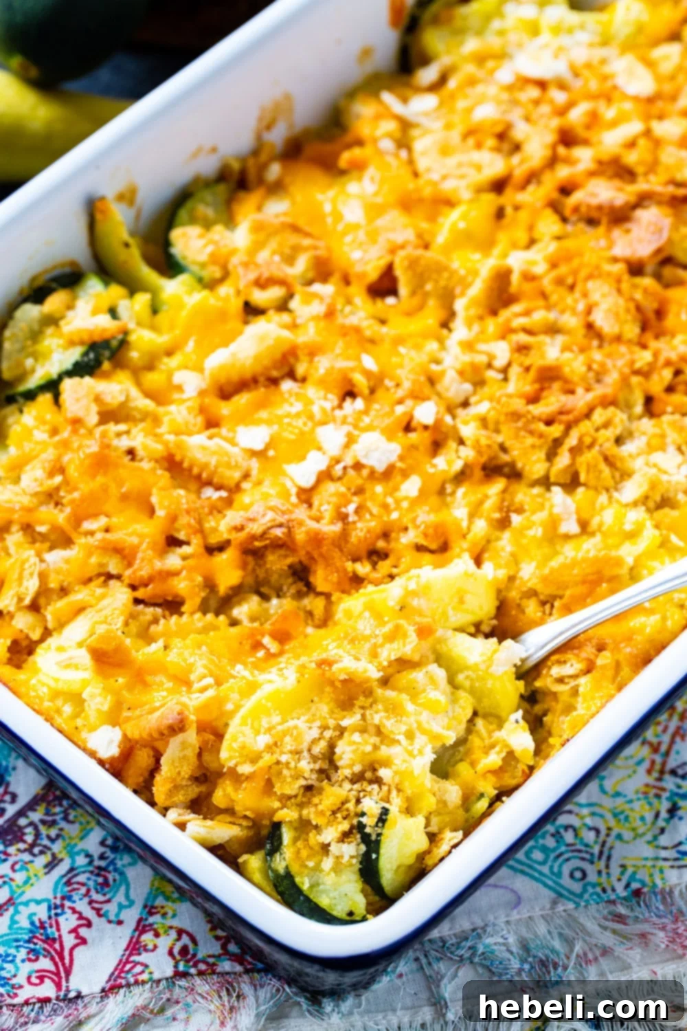 A beautiful Cheesy Squash and Zucchini Casserole with corn in a ceramic baking dish, showing its golden-brown topping and rich filling.