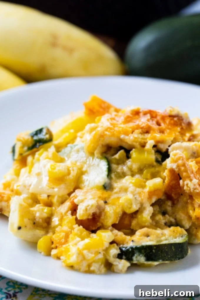 A close-up of a serving of Cheesy Squash, Zucchini, and Corn Casserole, showing the melted cheese, tender vegetables, and crispy cracker topping.