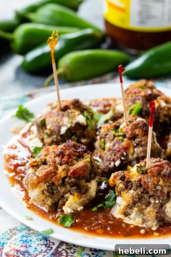 Close-up of a Jalapeno Popper Meatball cut in half, revealing the melted cream cheese and bits of bacon inside.