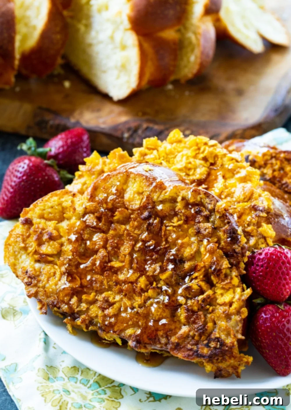 Thick slices of challah bread ready to be transformed into golden Crunchy French Toast, with a bowl of crushed cornflakes in the background, highlighting the key ingredient for the crispy coating.