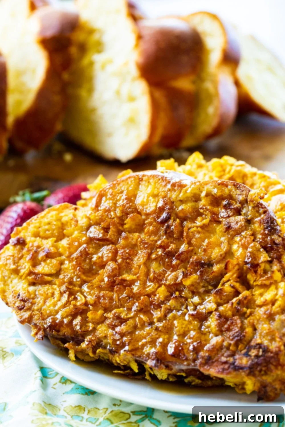 A close-up, mouth-watering detailed view of a single slice of golden Crunchy French Toast, perfectly showcasing the crisp cornflake coating and a hint of warm cinnamon.