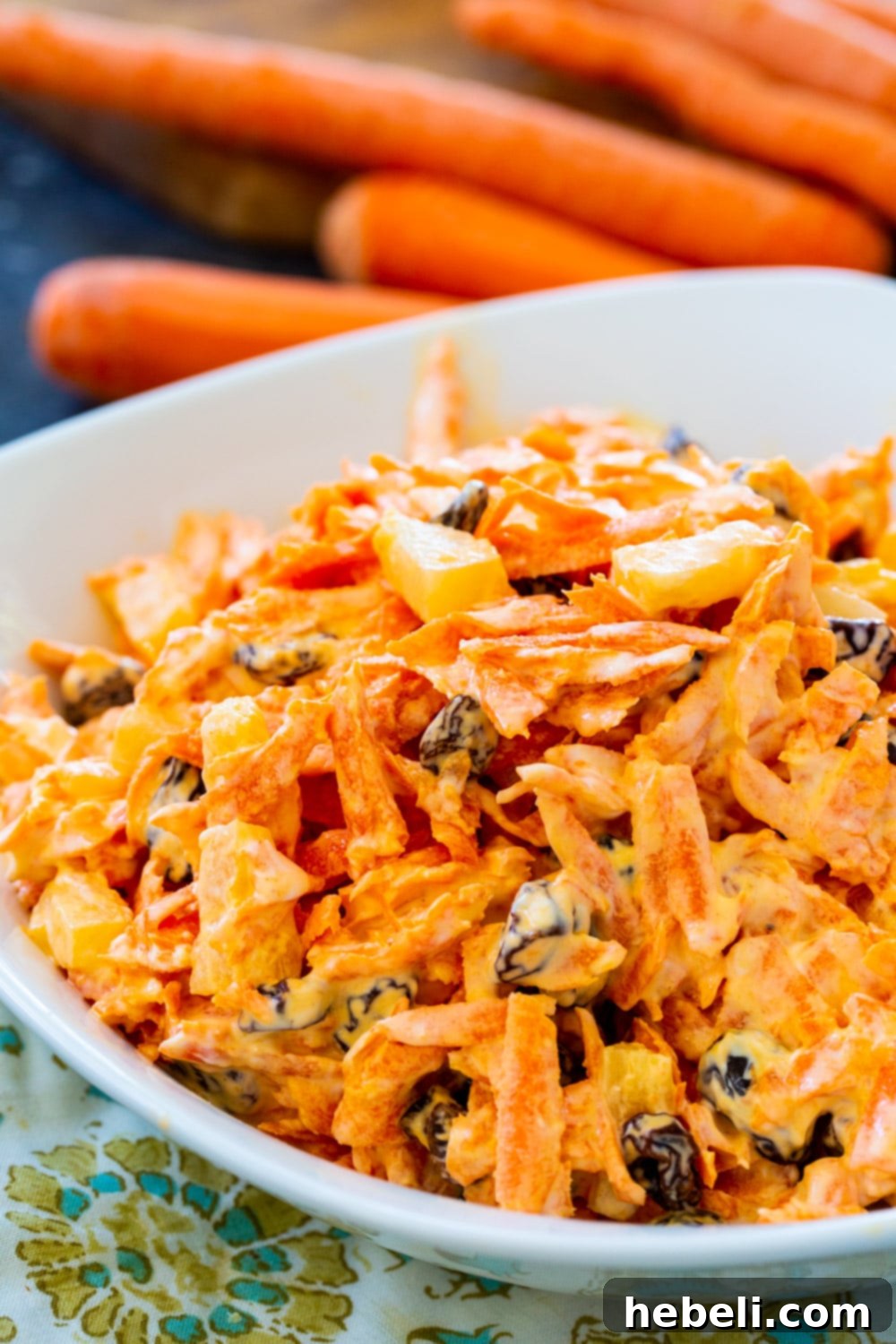 Sunshine Carrot Raisin Salad 4 A large white serving bowl filled with crunchy, sweet, and tangy Carrot Raisin Salad, ready for guests.
