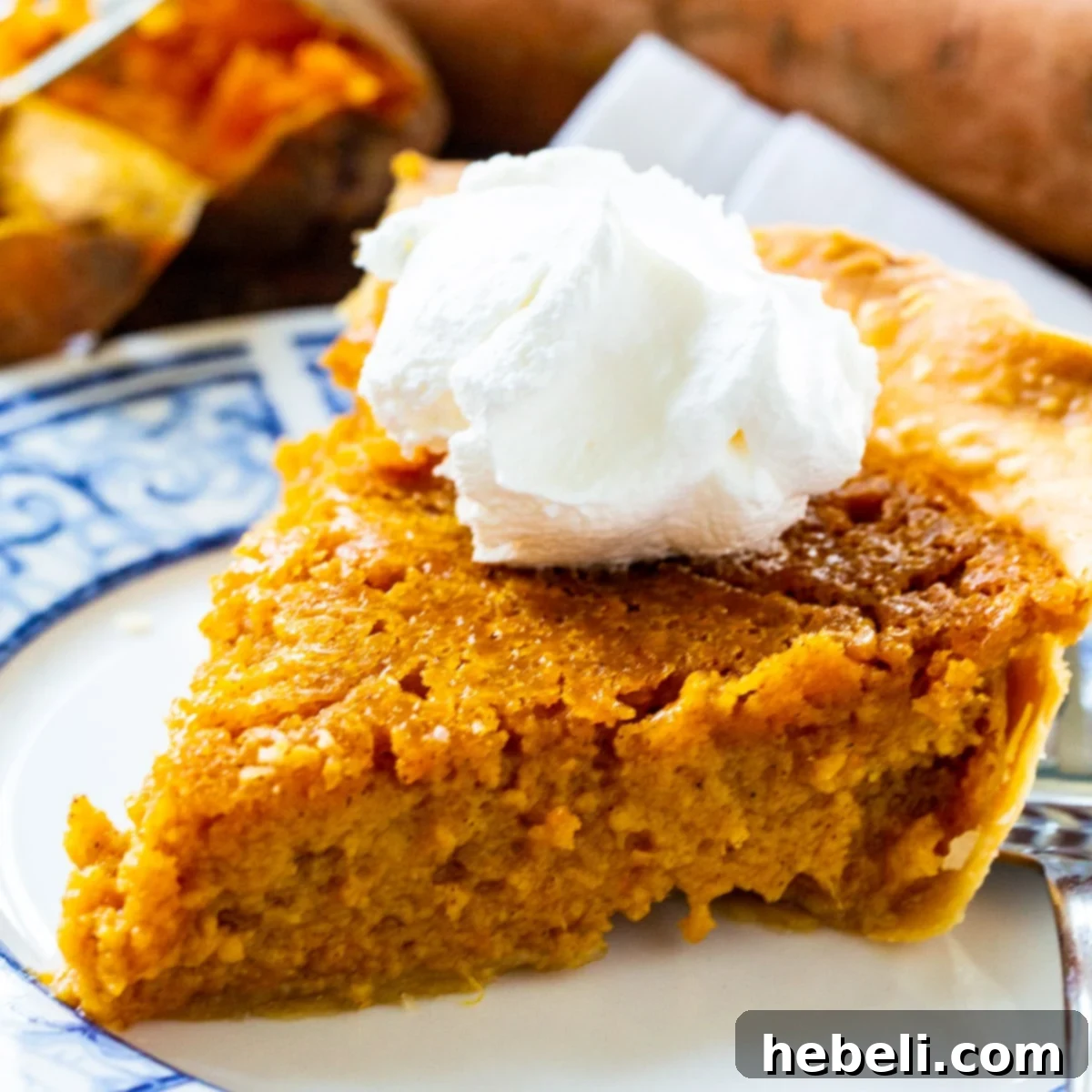 Slice of Southern Sweet Potato Pie topped with whipped cream, ready to be served on a festive table.