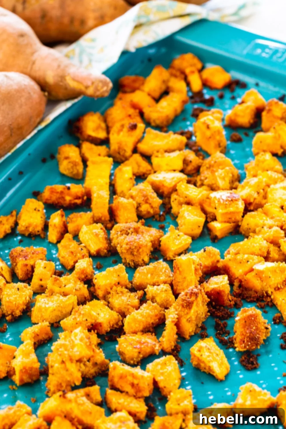 Close-up of golden brown Shake and Bake Sweet Potatoes on a baking sheet, showcasing their crispy coating.