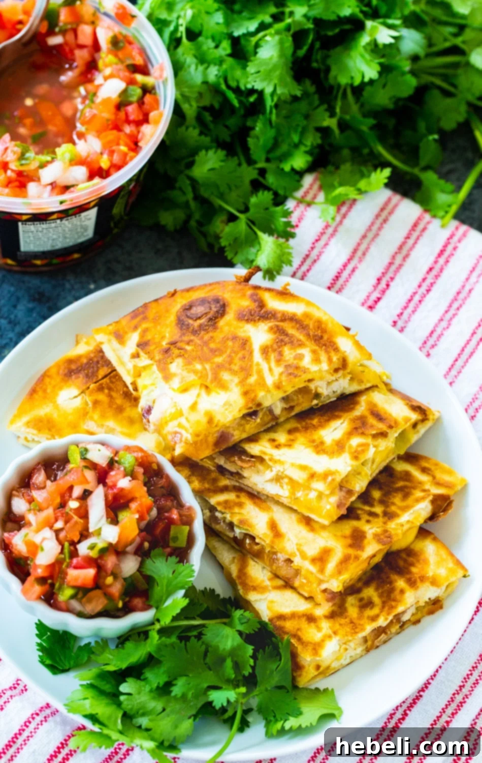 Delicious Chicken, Bacon and Ranch Quesadilla triangles elegantly arranged on a plate, accompanied by a small bowl of vibrant pico de gallo.