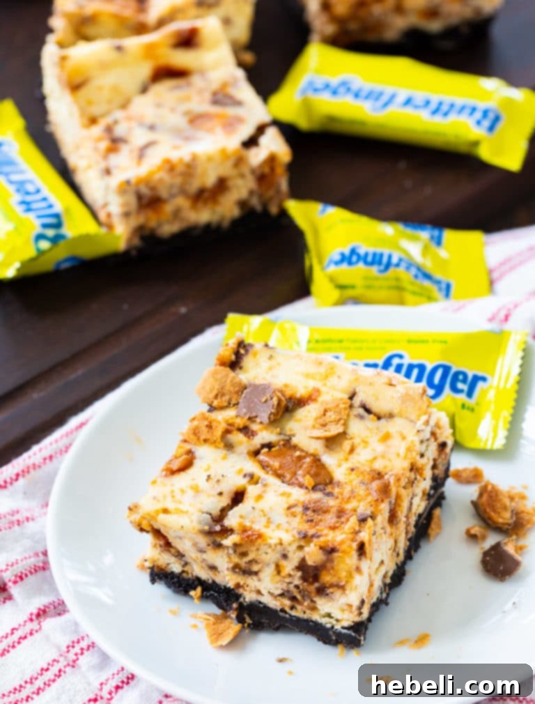 Decadent Butterfinger Cheesecake Bars 3 Close-up of Butterfinger Cheesecake Bars showing the layers of Oreo crust and cheesecake filling.