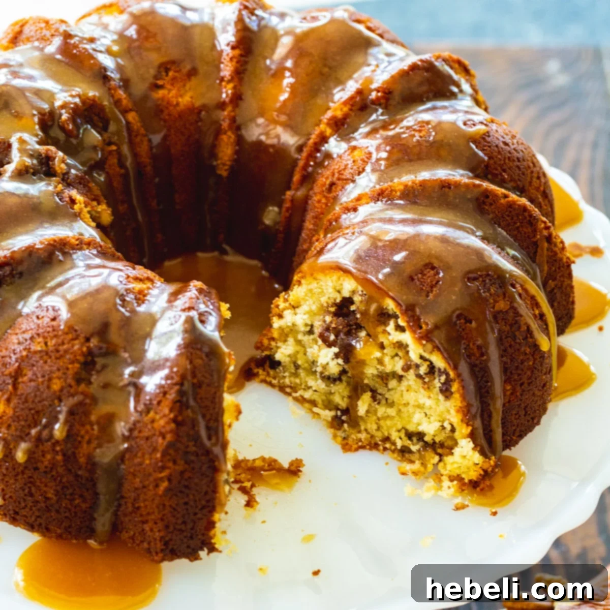 Pecan Pie Bundt Cake on a serving platter with several slices already cut, revealing the rich pecan filling inside.