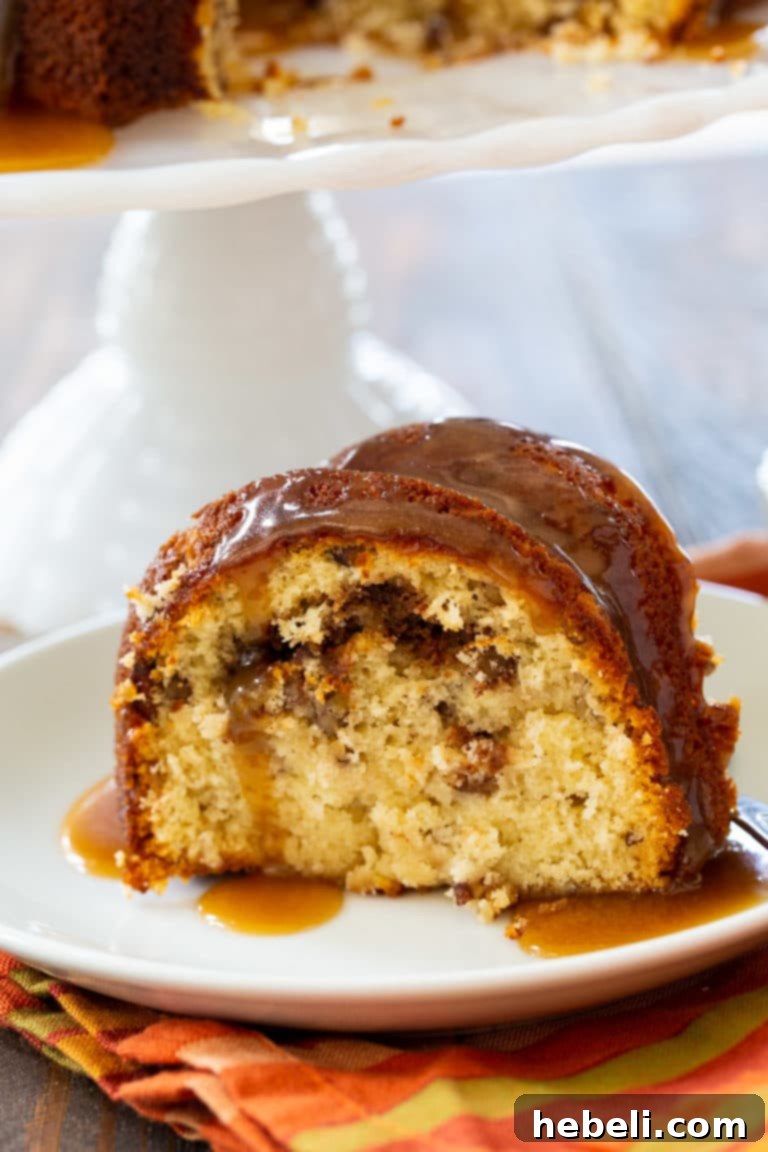 A beautifully sliced Pecan Pie Bundt Cake, showcasing the detailed inner pecan-cinnamon swirl and the glossy glaze.