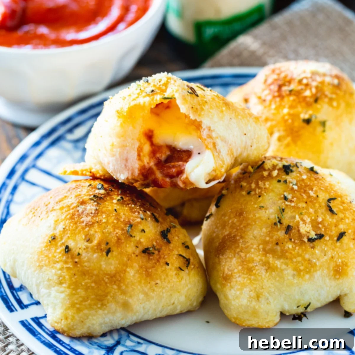 A plate overflowing with golden-brown Stuffed Crust Pizza Snacks, alongside a small bowl of rich red pizza sauce, ready for dipping.