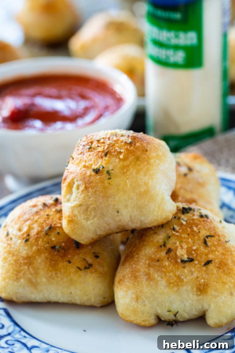 Close-up of a hand placing a cube of mozzarella cheese, slices of pepperoni, and a spoonful of pizza sauce onto a square of refrigerated pizza dough, ready to be wrapped into a Stuffed Crust Pizza Snack.