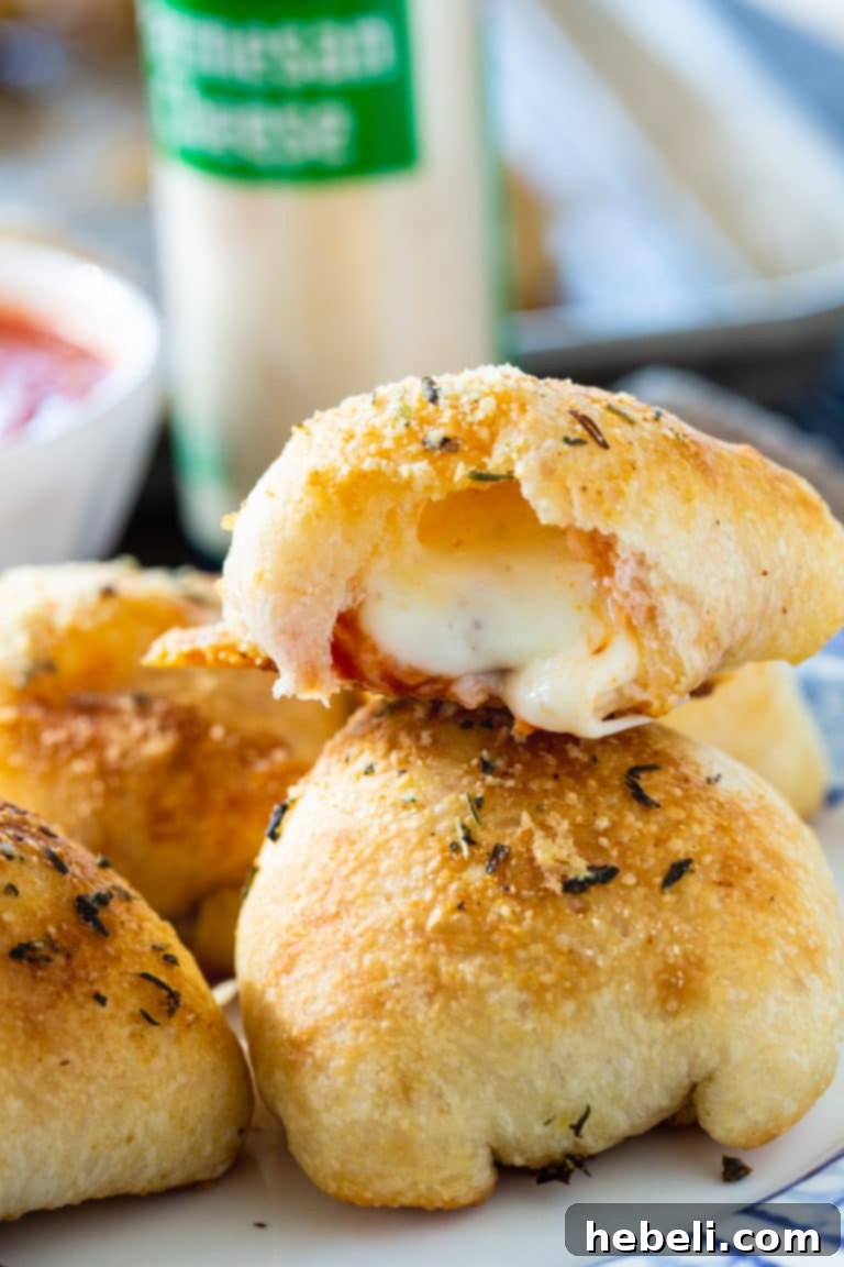 Rows of unbaked Stuffed Crust Pizza Snacks, brushed with herb and cheese topping, neatly arranged on a greased baking sheet, ready for the oven.