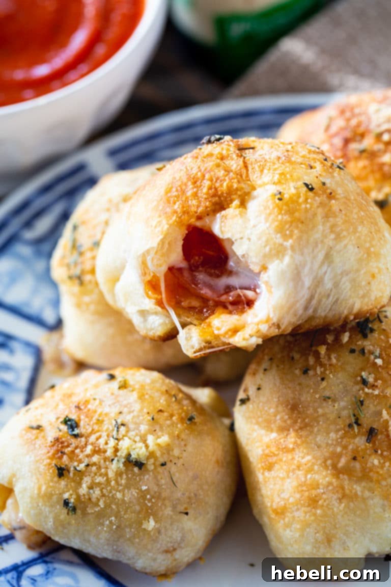 A close-up of a single Stuffed Crust Pizza Snack, showing its golden-brown exterior, dusted with herbs and cheese, with a hint of the cheesy, pepperoni filling peeking out.
