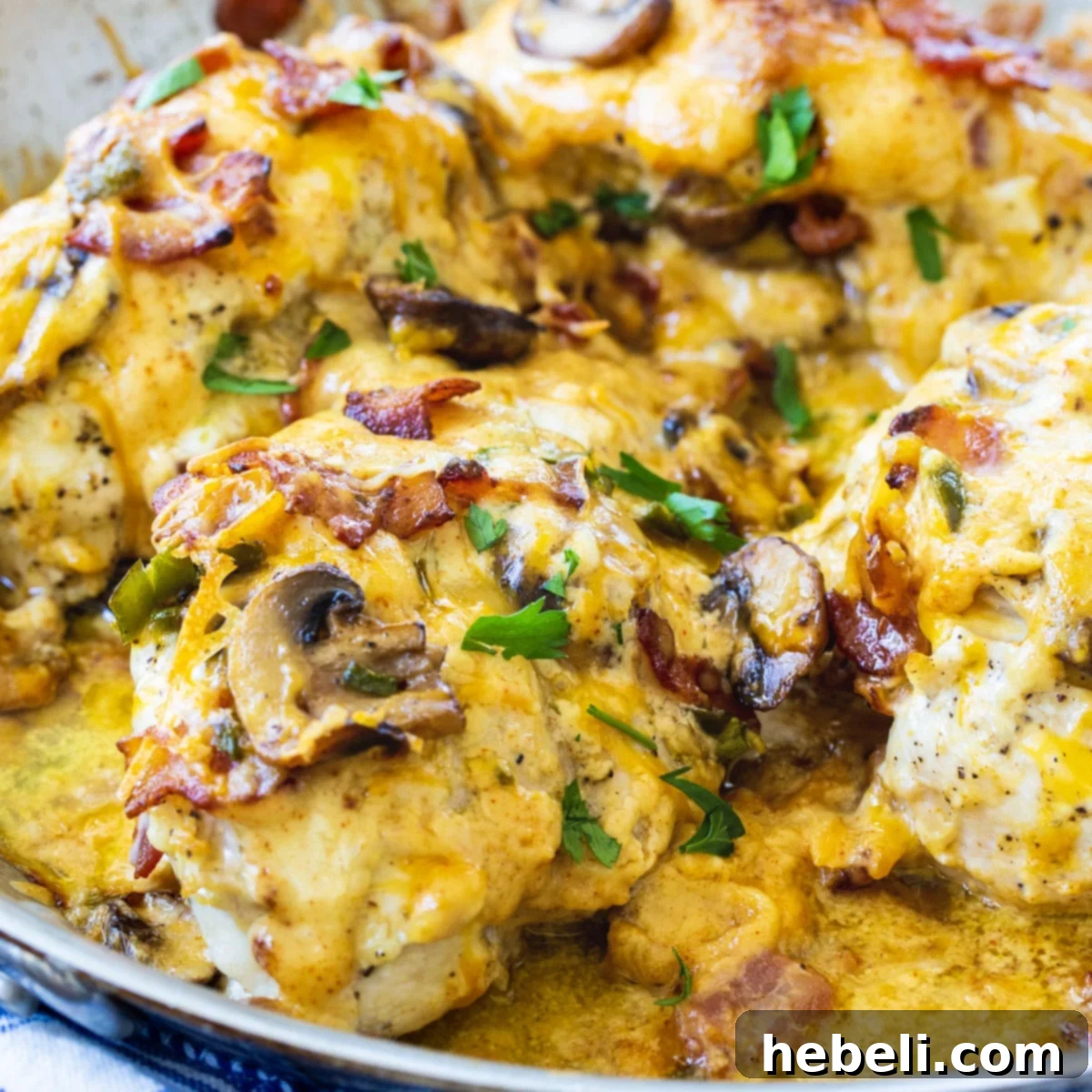 Ultimate Bacon Mushroom and Cheese Stuffed Chicken 2 Bacon, Mushroom, and Cheese Stuffed Chicken sizzling in a skillet, showcasing golden-brown chicken and a rich filling.