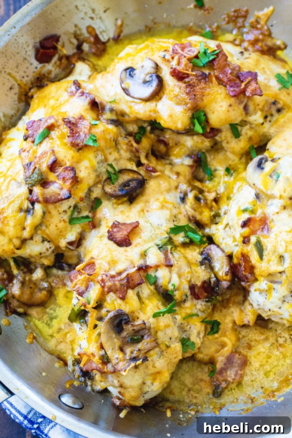 Ultimate Bacon Mushroom and Cheese Stuffed Chicken 3 Close-up of cooked stuffed chicken breasts, golden-brown and topped with melted cheese and mushrooms.