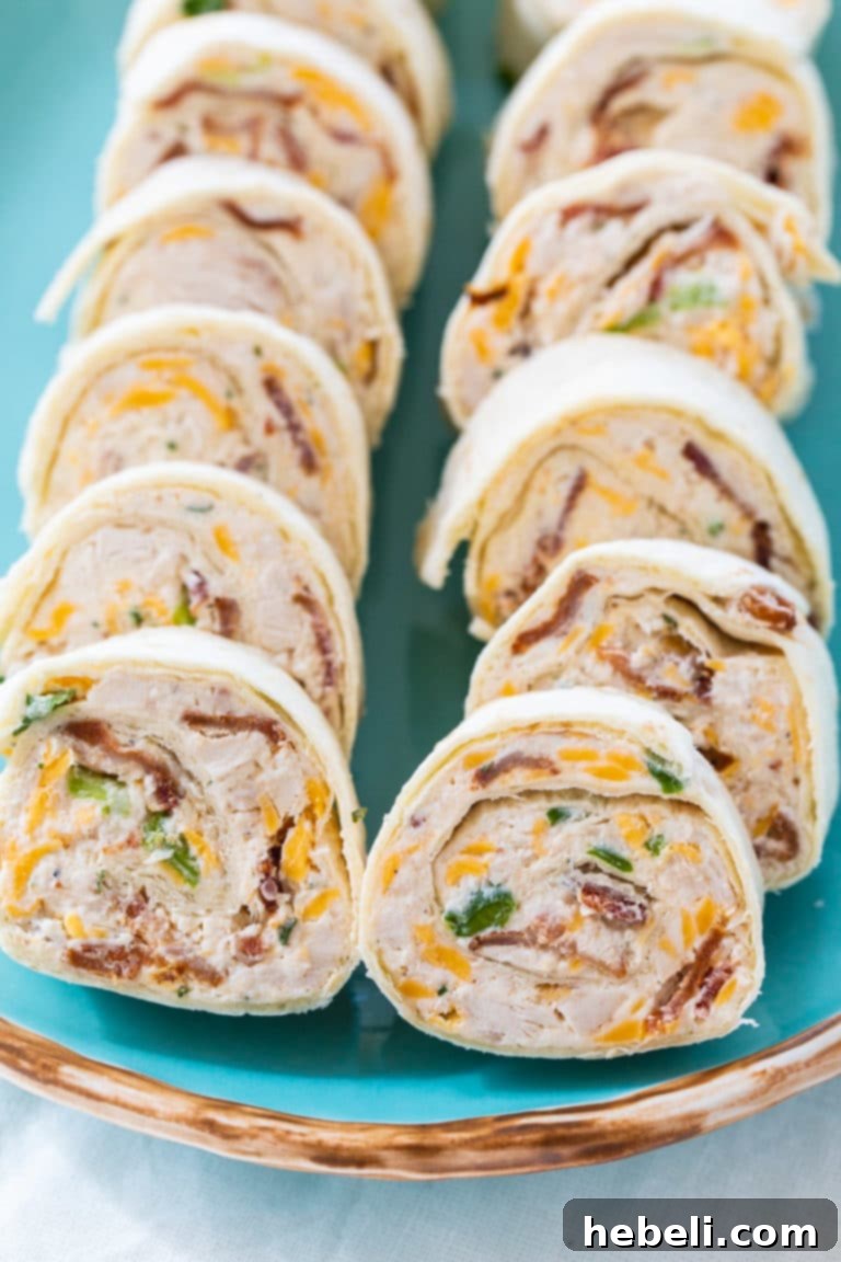 Close-up shot of individual Chicken, Bacon, and Cheddar Pinwheels showing the creamy filling and vibrant colors, highlighting them as an easy party appetizer or gameday snack.