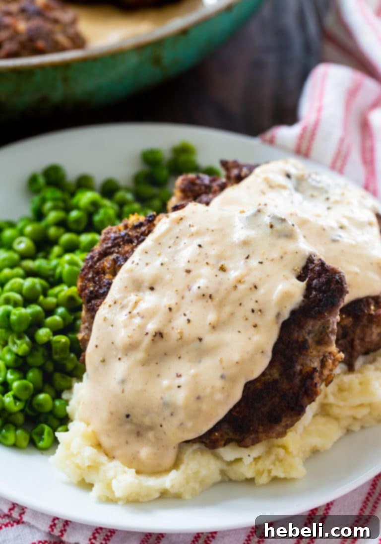 Hamburger Steaks with Country Gravy served on a white plate, highlighting the tender beef patties and creamy sauce, garnished with fresh herbs, signaling a quick and satisfying meal.