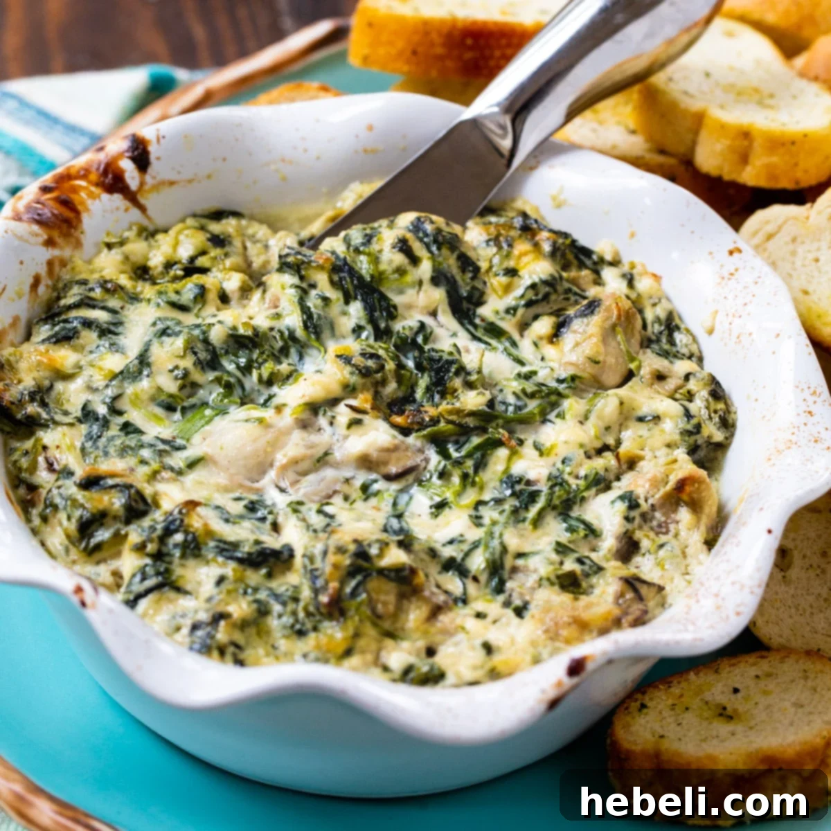 A golden-brown Oysters Rockefeller Dip, served in a small baking dish, ready to be enjoyed with crusty bread.